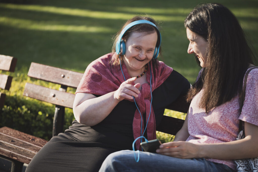 Woman with Down Syndrome and her friend having fun in a park. Woman with Down Syndrome and her friend having fun in a park.
