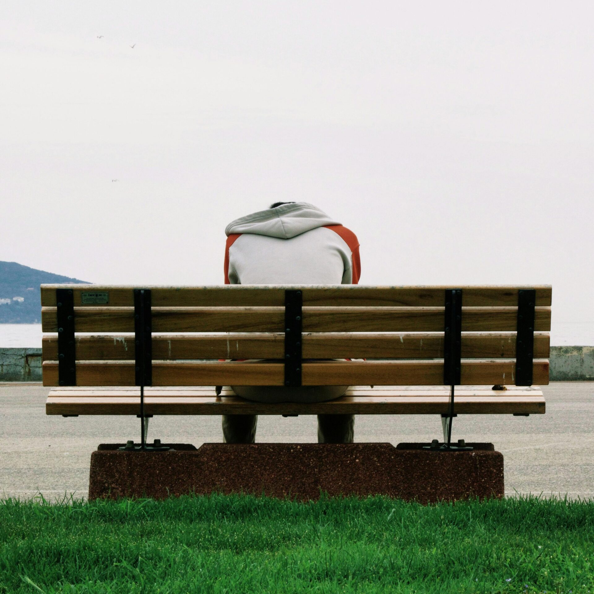 crisis advocate support for people with disabilities auckland A person sitting on a bench in a park, looking sad and in need of help.