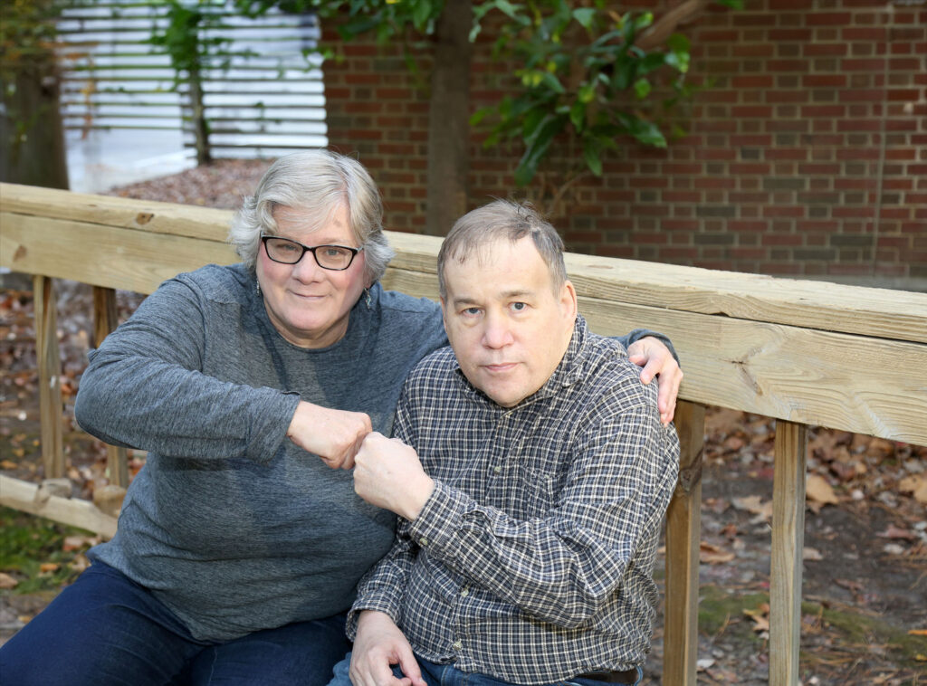 disability-advocacy-Auckland-Advocate-and-friend-sitting Two people sitting outside giving each other a fist bump